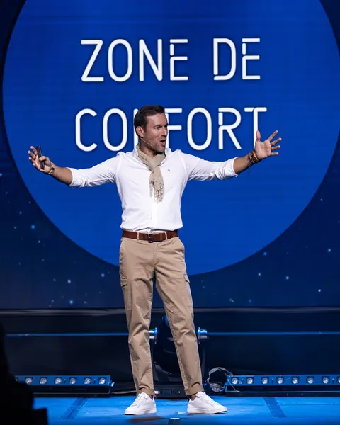 Nicolas Felger sur scène sous un disque bleu « Zone de confort »